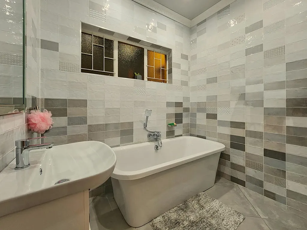 Modern bathroom with freestanding bathtub, sink, and tiled walls