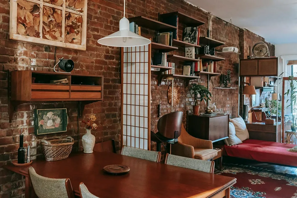 Rustic living room with exposed brick wall, wooden furniture, bookshelves, and cozy decor